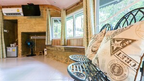 A cozy room with a stone fireplace, a ceiling fan, and a window with curtains. - Baandin Chiewlarn Resort (Ban Ta Khun)