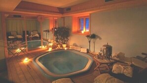 A hot tub in a room with a wooden floor, a window with curtains, and a plant. - Hotel Baita Fiorita (Valfurva)