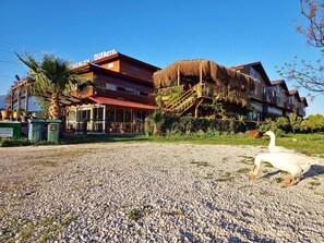 A hotel with a thatched-roof structure, a covered outdoor seating area, and a gravel ground. - Dufa Apart Bungalow (Demre)
