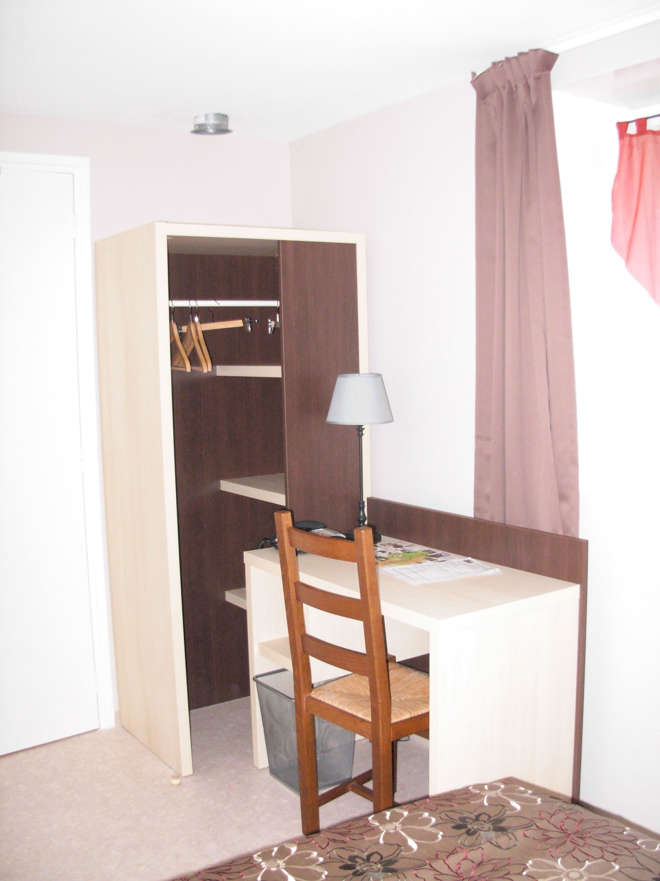 Un dormitorio pequeño con escritorio, silla y armario.