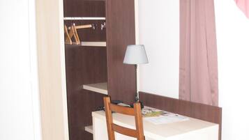 Un dormitorio pequeño con escritorio, silla y armario.