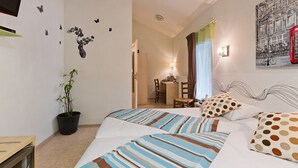 A hotel room with a bed, a desk, a chair, a potted plant, and a wall-mounted TV. - Hotel Restaurant De La Dore (Vertolaye)