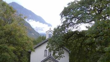 Una iglesia con un campanario, rodeada de árboles y un sendero pavimentado que lleva a la entrada.
