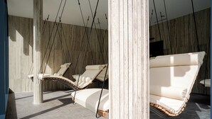 A modern interior with a hanging lounge chair and a cushioned bench.