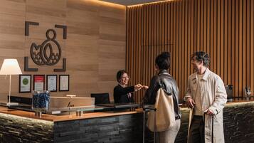Un mostrador de recepción con pared de paneles de madera, premios enmarcados y una lámpara moderna.