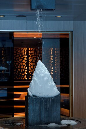 Eine Schneeskulptur in einem modernen Innenraum mit geometrischem Wandmuster und einer Glastür.