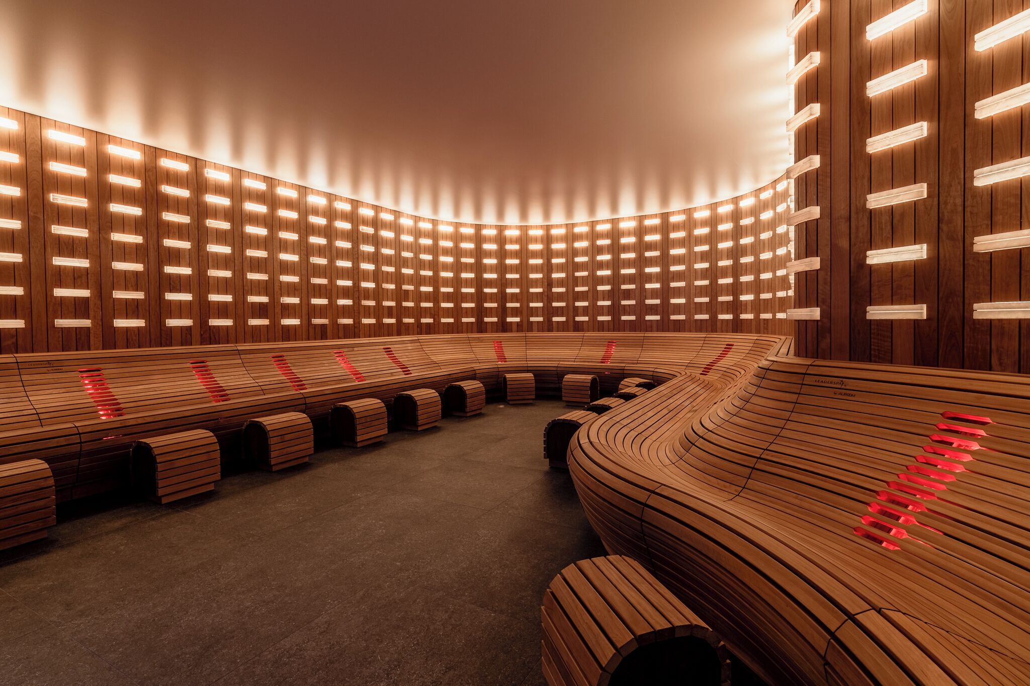 A modern interior with curved wooden seating and illuminated panels.