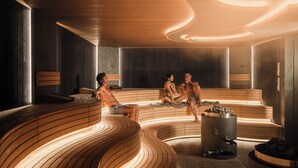 A sauna with wooden benches and a central heating element.