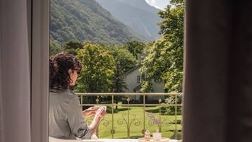 Una persona sentada a una mesa con vistas a un paisaje verde exuberante y montañas al fondo.