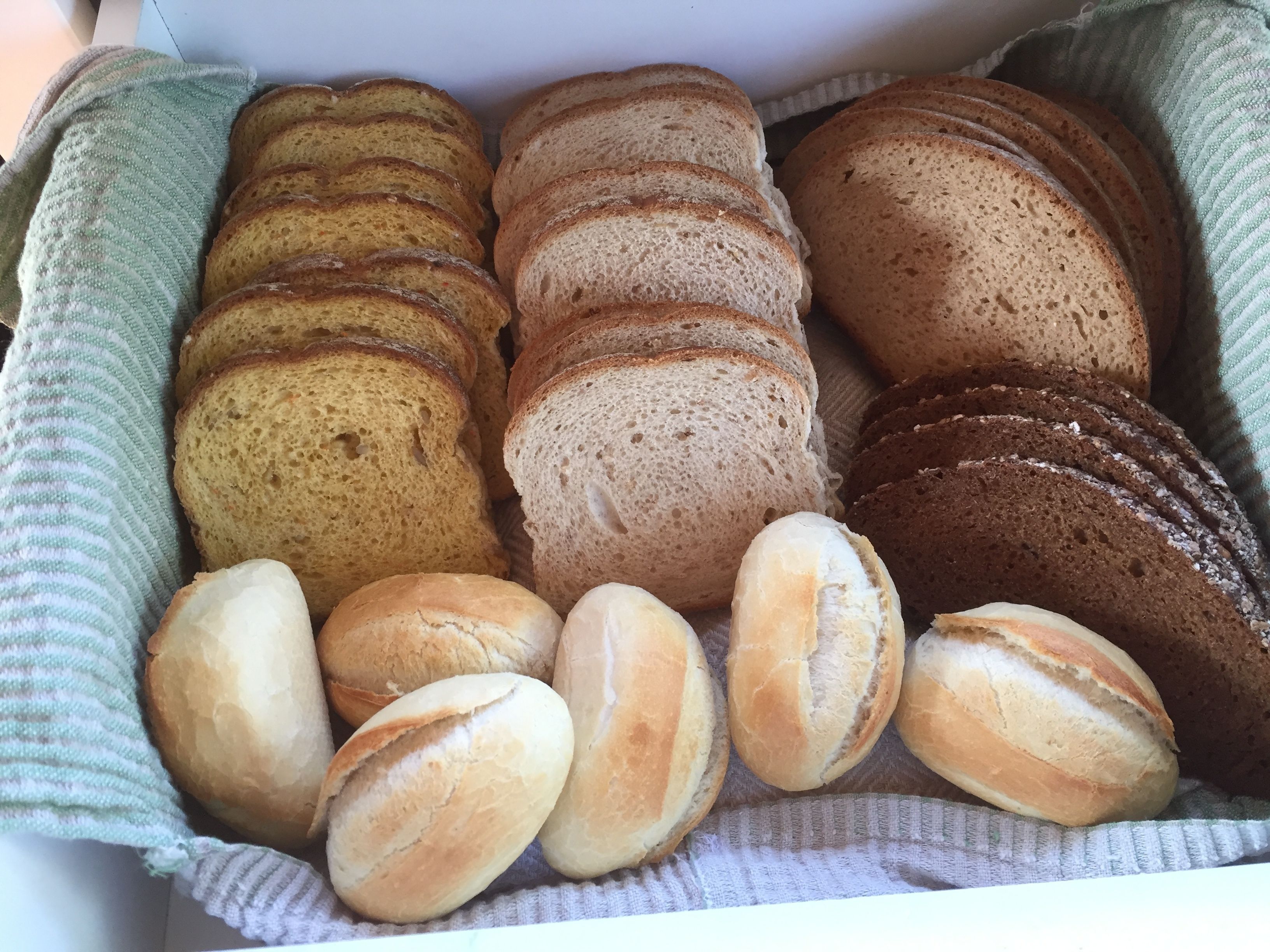 A box of assorted bread varieties including baguettes, rolls, and dinner rolls.