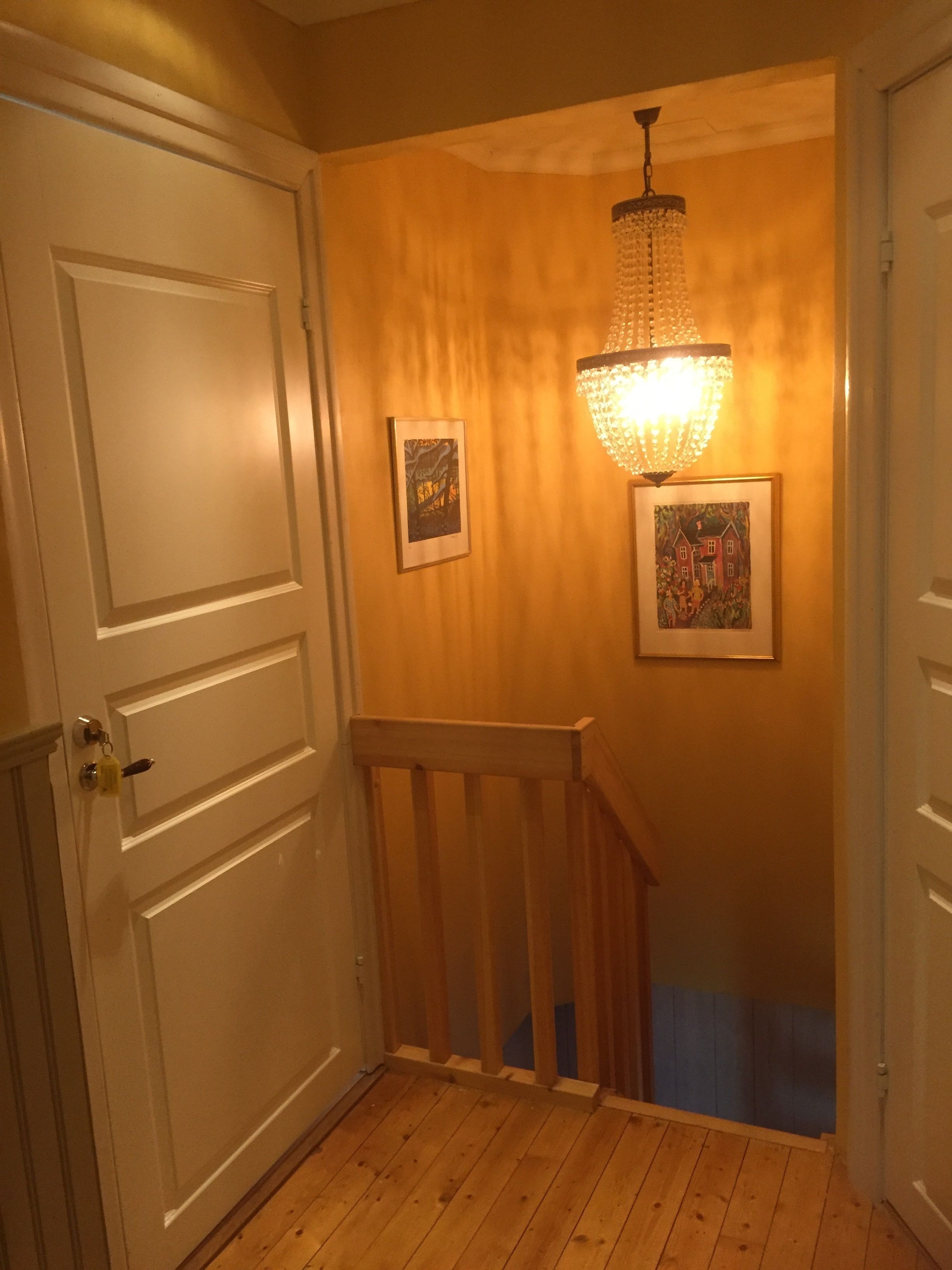 A hallway with wooden flooring, white doors, and a staircase with a wooden railing.