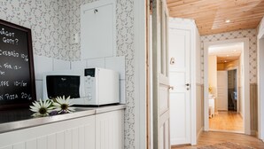 Una cocina con microondas, un menú en pizarra y papel tapiz floral.