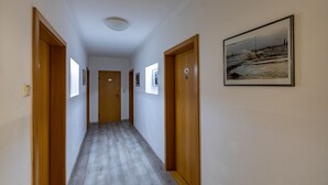 Un pasillo con puertas de madera, un cuadro en la pared y una lámpara en el techo.