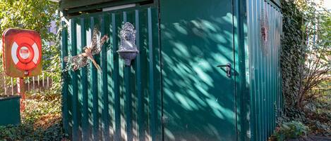 Un cobertizo utilitario verde con puerta y cerradura de metal, y un ventanal pequeño.