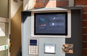 A self-service kiosk with a screen displaying "Book your Key" and a keypad below. - Stadt-gut-Hotel Großer Kurfürst (Emden)