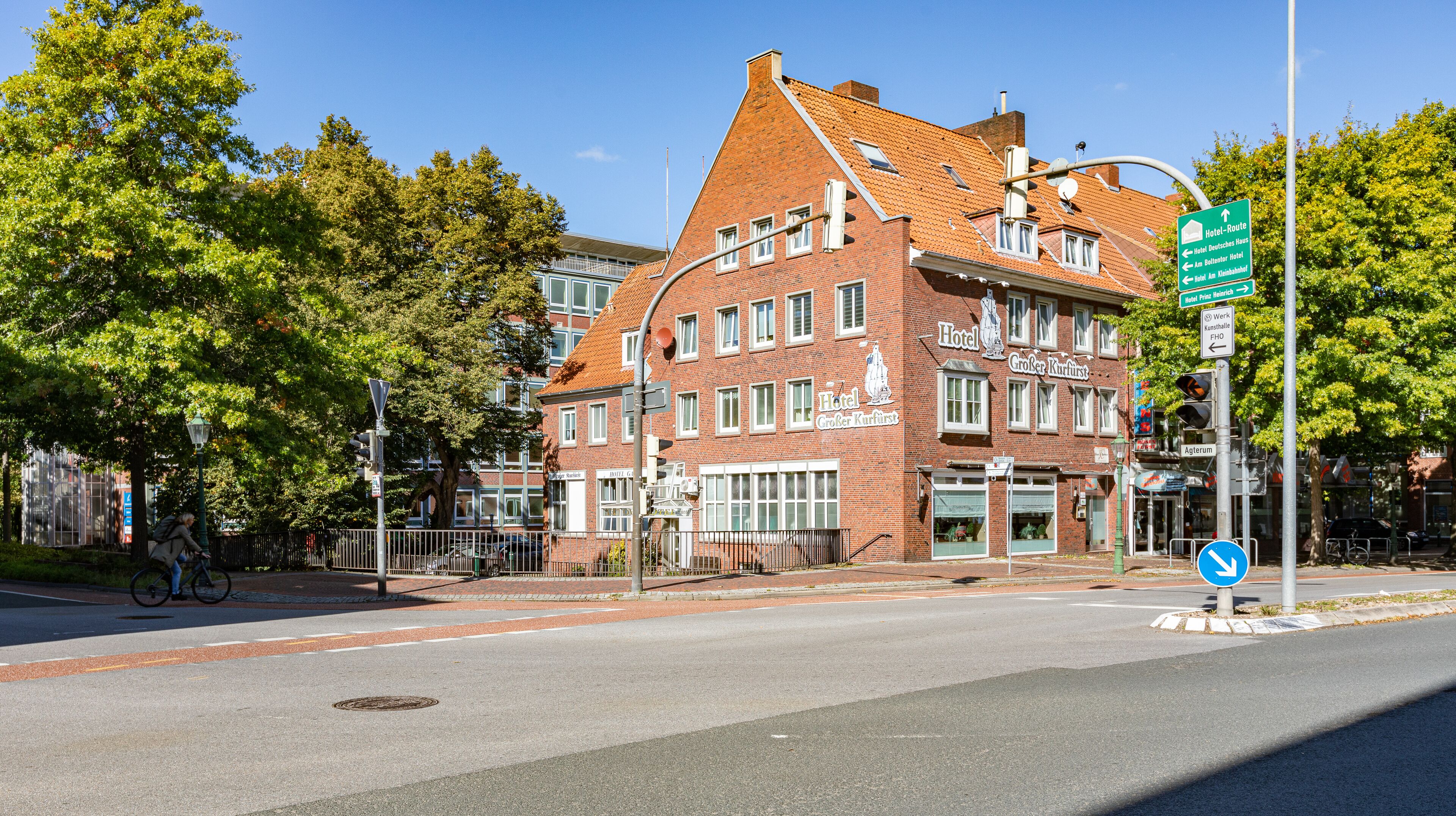 A historic building with a red brick facade, multiple windows, and a sign indicating it is a hotel.