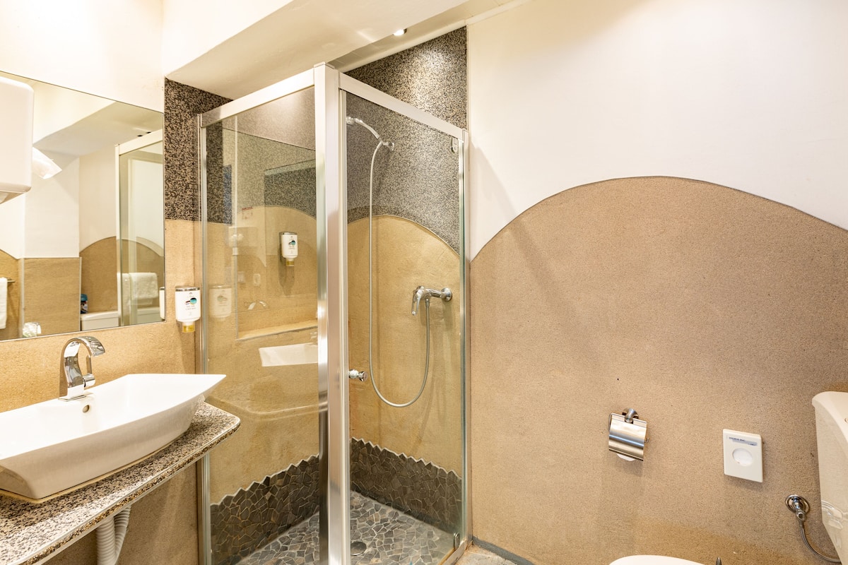 A bathroom with a glass-enclosed shower, a sink, and a toilet.