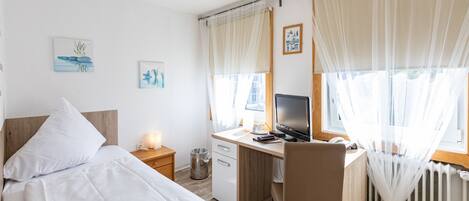 A bedroom with a bed, desk, chair, and a computer.