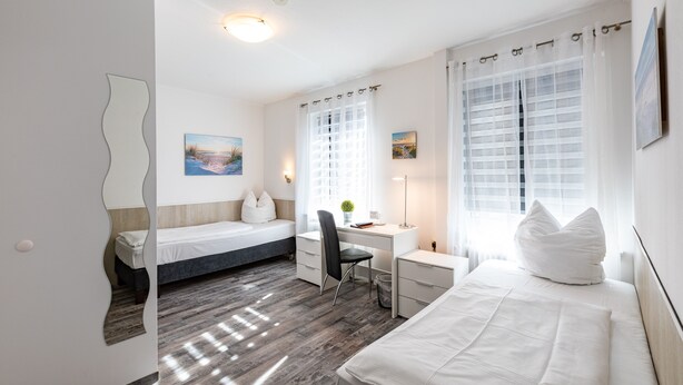 Un dormitorio moderno con dos camas individuales, un escritorio y una silla.