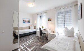 A modern bedroom with two single beds, a desk, and a chair. - Stadt-gut-Hotel Großer Kurfürst (Emden)