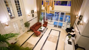 Um hall amplo com grande área de estar, balcão de recepção e vista para a área da piscina.