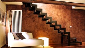 Una sala de estar moderna con un sofá blanco, una escalera de madera y un radiador.