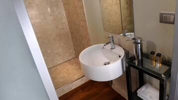 Une salle de bain moderne avec un lavabo blanc, un meuble-lavabo en verre, un miroir et un espace douche.