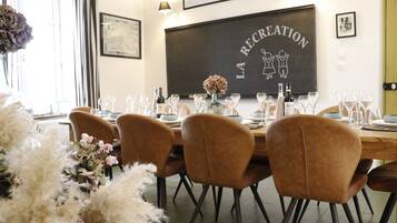 A dining area with a long table set for a meal, surrounded by chairs.