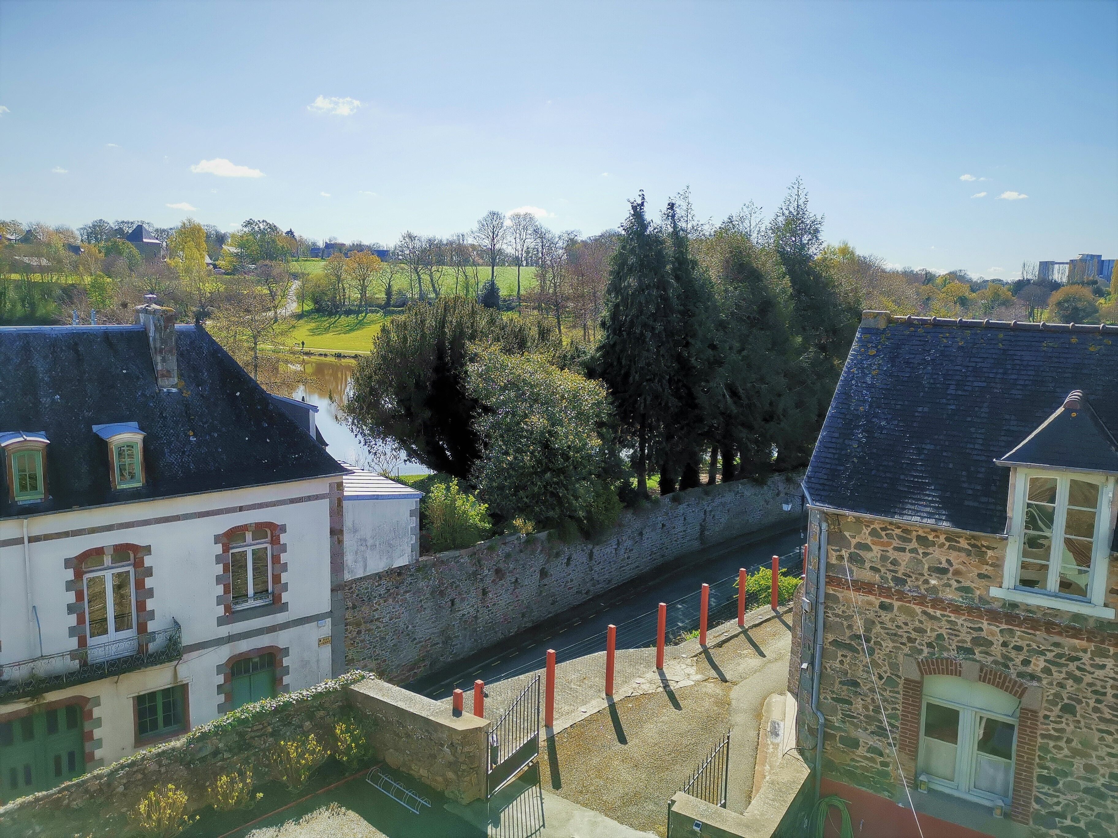 A riverside view of a town with stone buildings, a stone wall, and a canal.