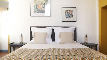A neatly made bed with patterned bedding, two bedside tables with lamps, and two framed artworks on the wall.