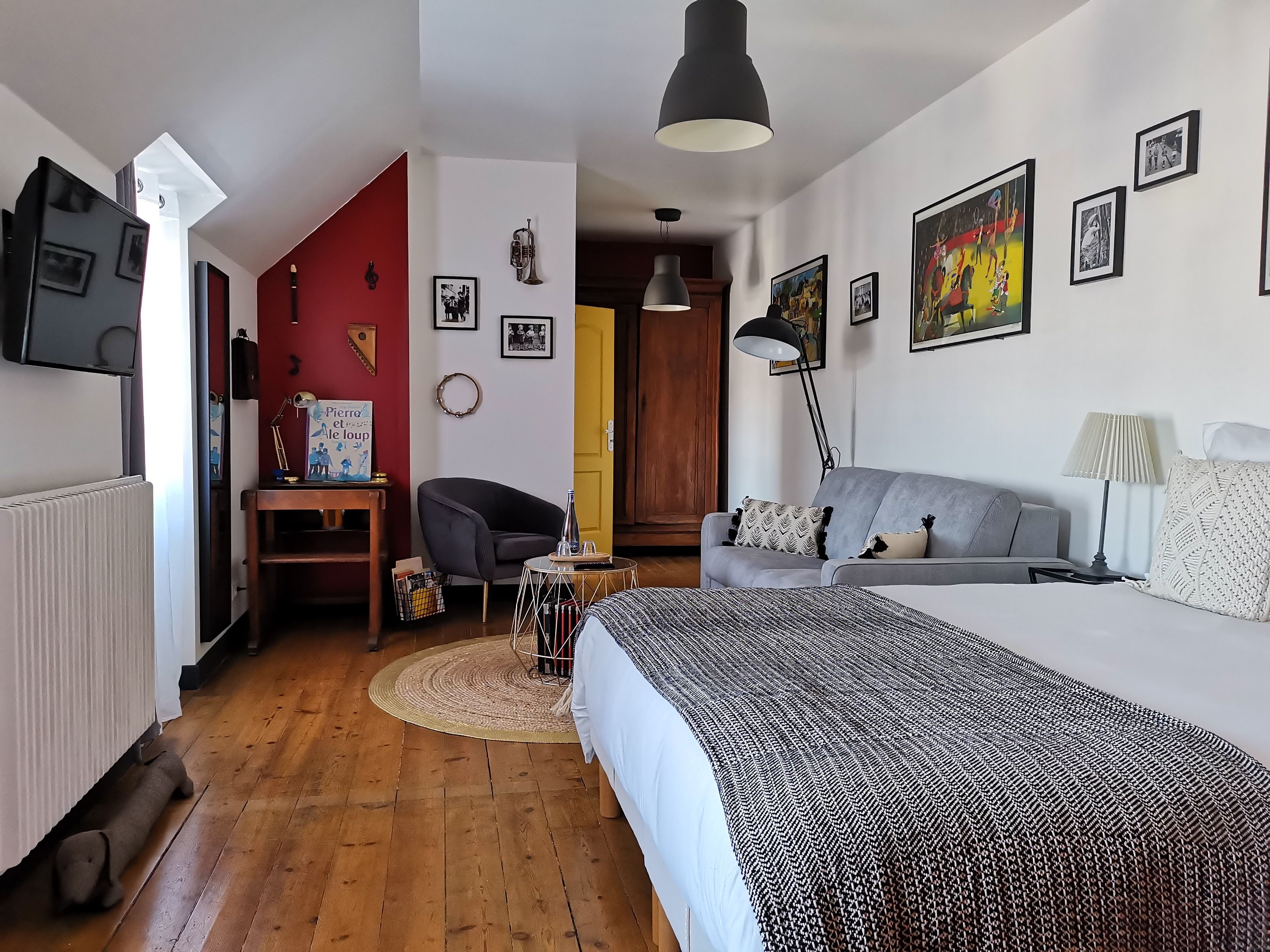 Un dormitorio moderno con una cama, un sofá gris, un escritorio y una silla.