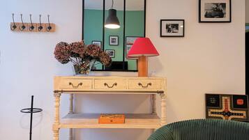 A room with a wooden console table, a mirror, a red lamp, and a chessboard.