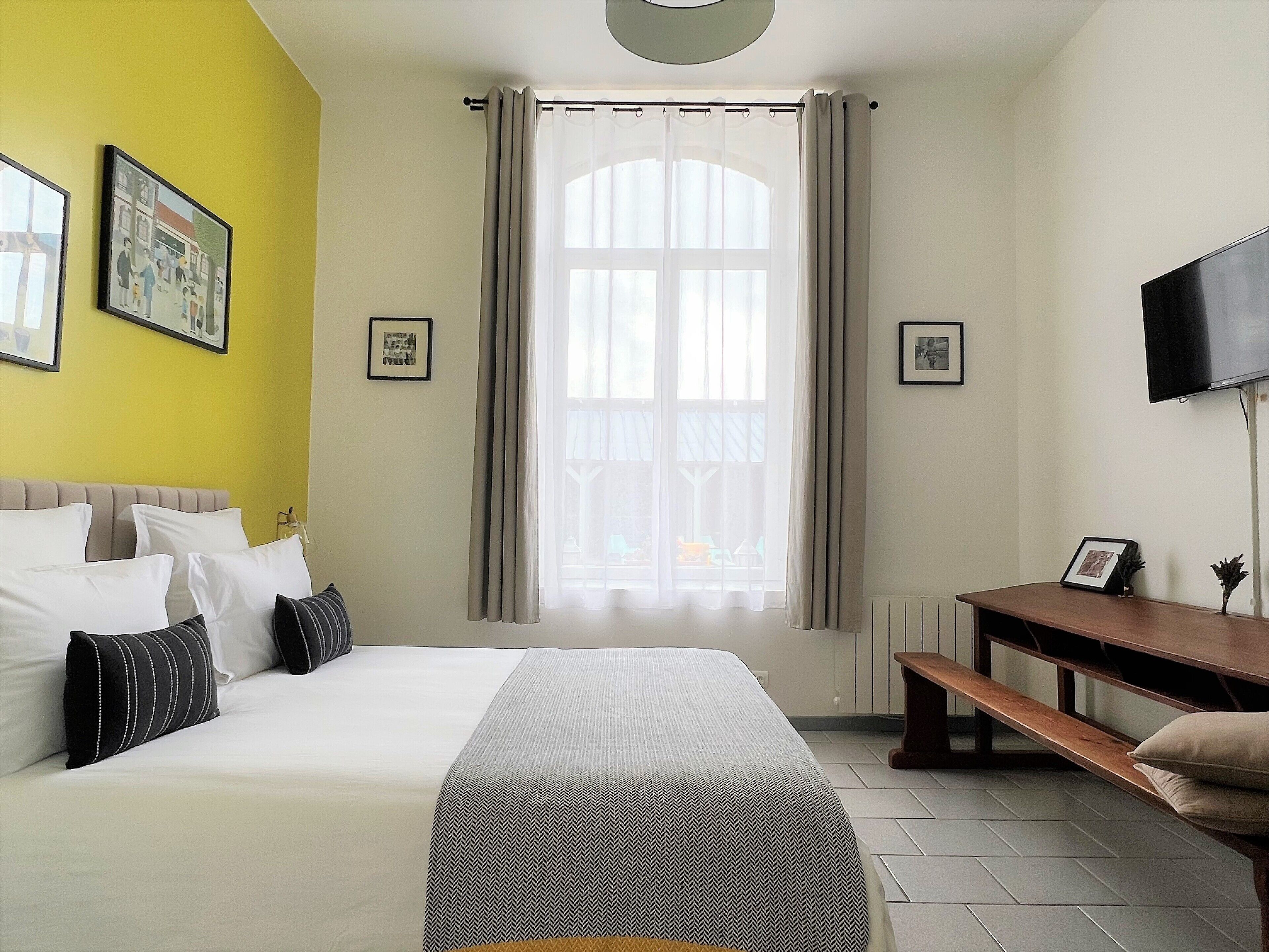 Un dormitorio con cama, escritorio, banco y televisor.