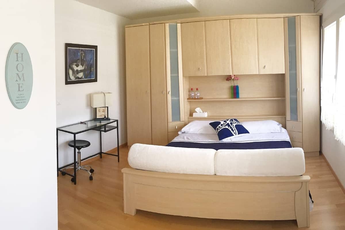 A bedroom with a bed, a desk, and a wardrobe.