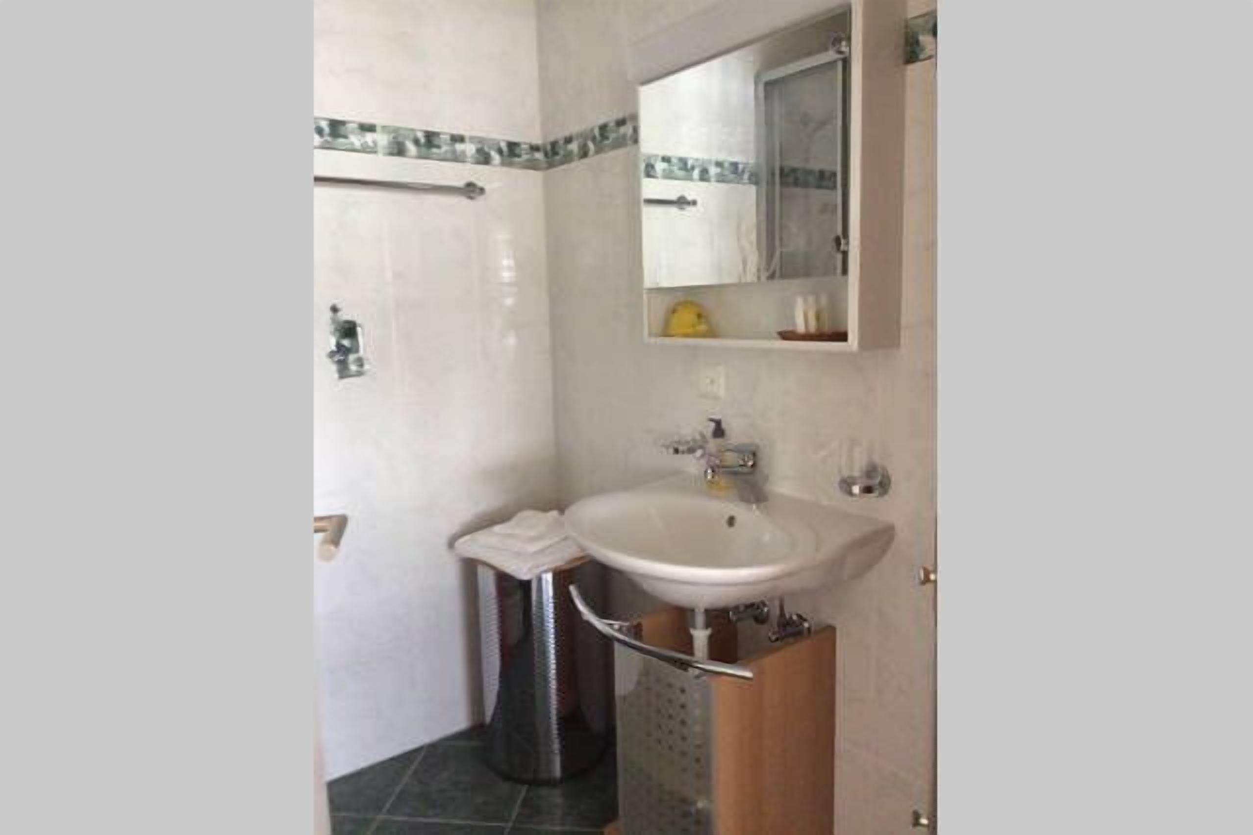 A bathroom with a white sink, mirror, and tiled walls.