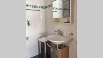 A bathroom with a white sink, mirror, and tiled walls.
