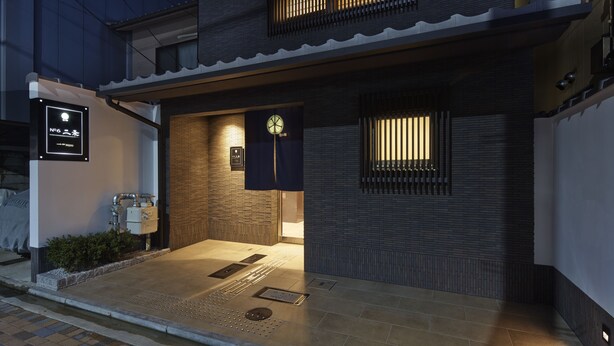 A traditional Japanese-style building with a tiled entrance, a clock, and a signboard. - No6 Nijo (Kyoto)