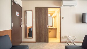 A hotel room with a wooden door, a mirror, a television, a small table, and a bathroom visible through an open door. - No6 Nijo (Kyoto)
