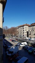 Vista de la calle con coches estacionados, un tranvía y edificios con balcones.