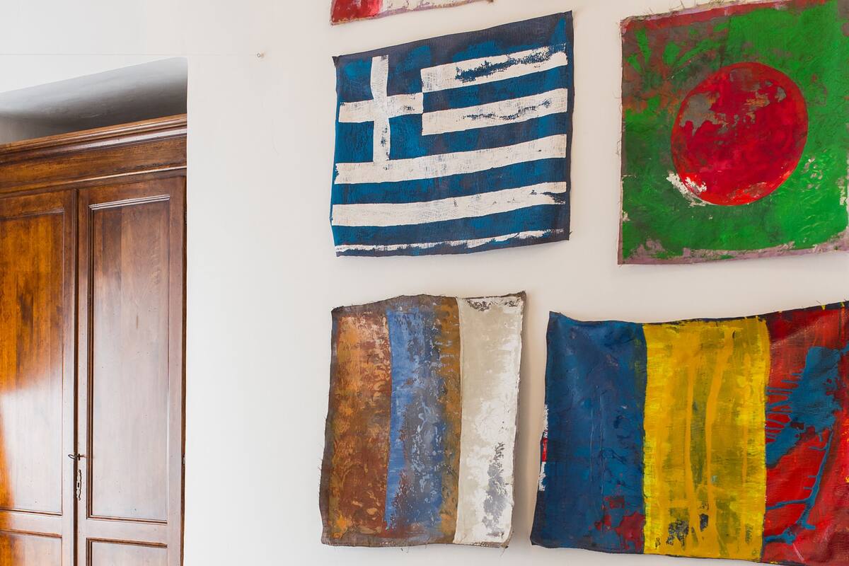 A room with a bed, a wooden wardrobe, and several wall-mounted artworks.