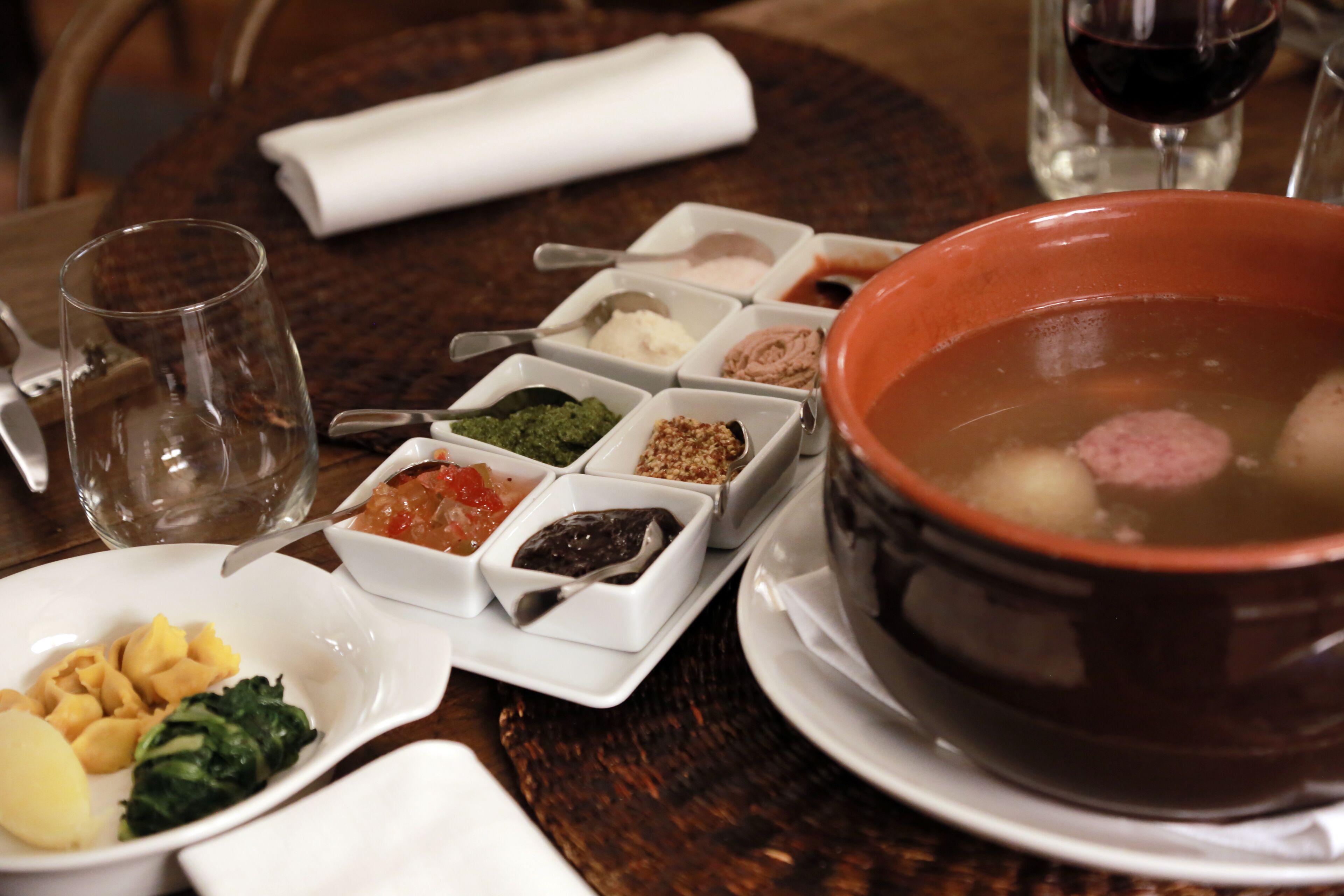 Une table à manger avec différents plats, notamment un bol de soupe, des pâtes et de petits ramequins contenant des condiments.