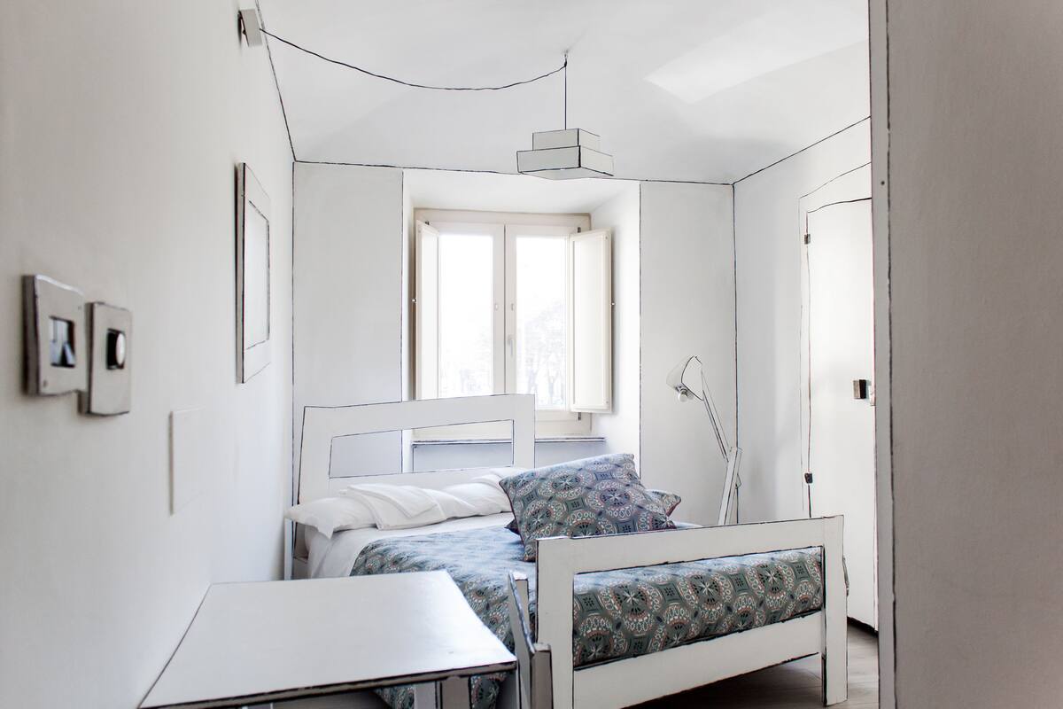 A minimalist bedroom with a bed, bedside table, and a window.