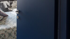 Uma porta azul escura com o número 24, um cobreleiro estampado e uma parede com um mural em preto e branco.