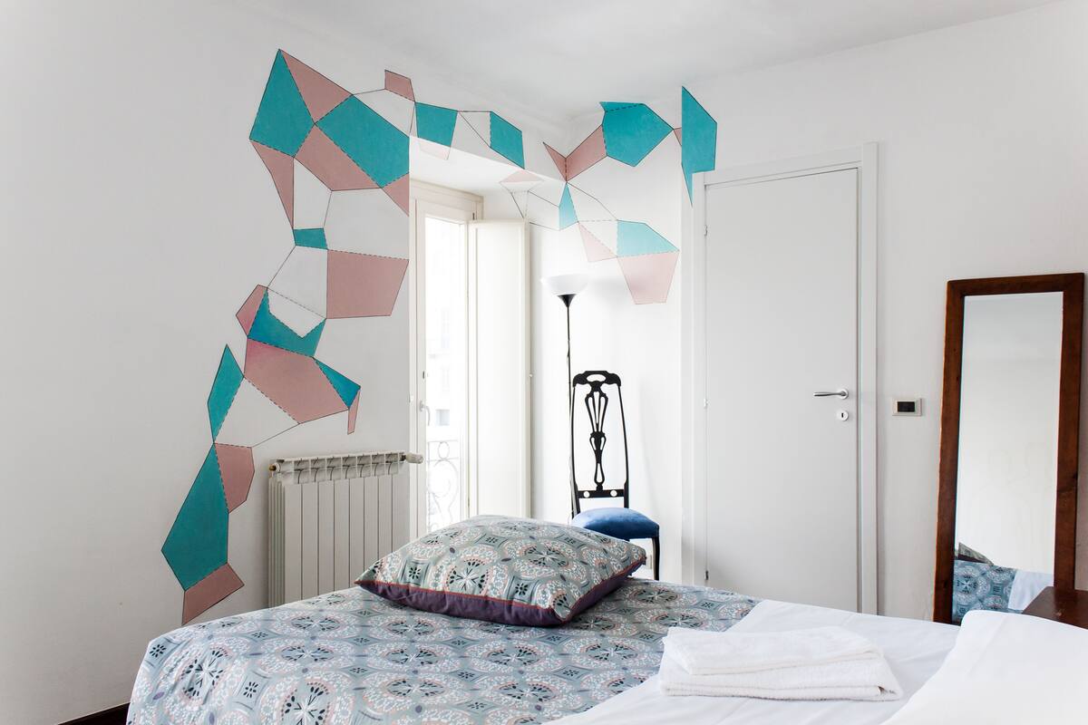 A bedroom with a bed, a chair, a radiator, and a door.