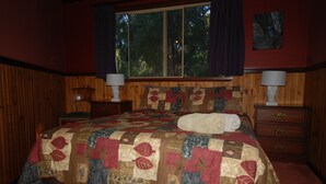 Quarto com uma cama grande, painéis de madeira, duas mesas de cabeceira com luminárias e uma janela com cortinas.