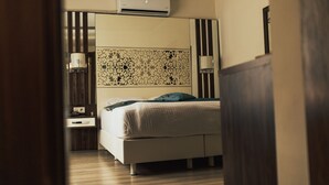 Un dormitorio moderno con cama, mesitas de noche, equipo de aire acondicionado y un panel decorativo en la pared.