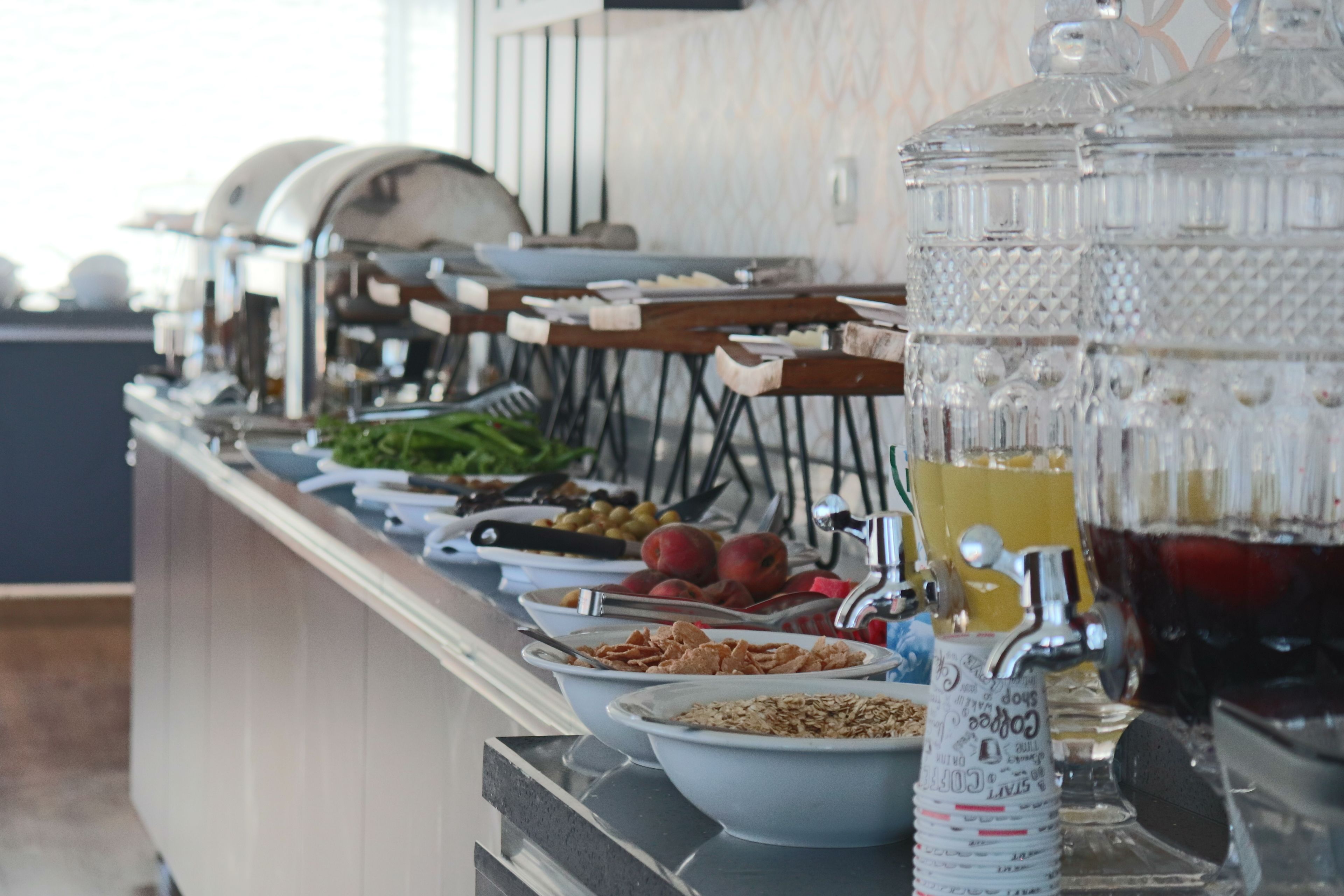 A buffet with various food items and a beverage dispenser.