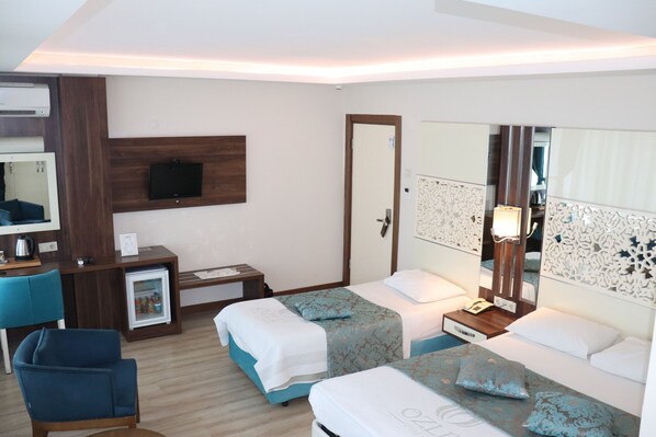 A hotel room with two beds, a desk with a computer, a chair, a TV, and a minibar.