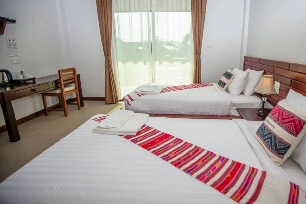A hotel room with two beds, a desk, and a chair.