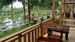 Um deck de madeira com bancos oferece vista para um lago, cercado por vegetação exuberante.